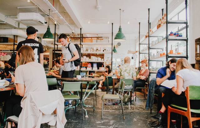 Photo of people in a coffeeshop being social in person and on their phones.